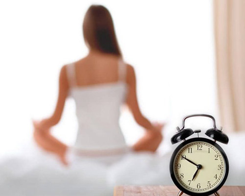LOW ENERGY & POOR SLEEP Woman in background with alarm clock